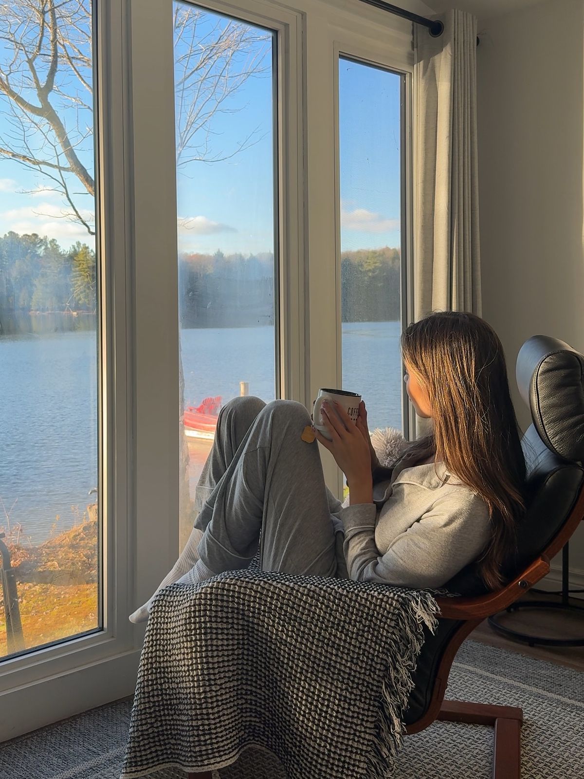 Woman enjoying a warm drink beside a lakeside window